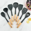 Silicone kitchenware set with wooden handles. Kitchen tools: silicone spatula, strainer, frying spatula